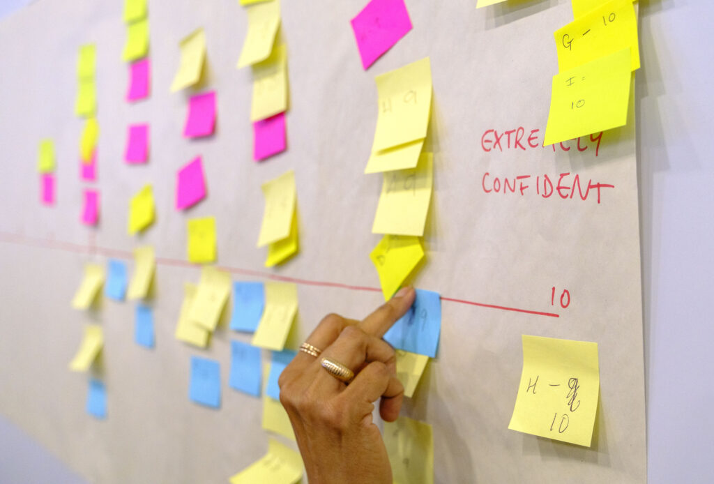 Post-it notes being placed on a written scale up to "10 - Extremely confident"